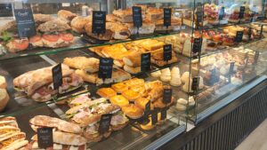 Delicious-looking sandwiches and cakes lined up in the glass-fronted display case in Grants bakery and tea shop.